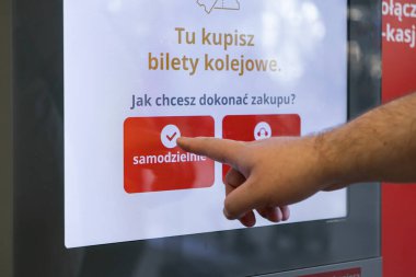 Poznan, Polonya - 13 Temmuz 2025: Bir kişinin elinin dijital dokunmatik ekranlı self-servis büfesiyle etkileşime girdiği yakın çekim görüntüsü, tren bileti almak için 'samodzielnie' yi kolaylıkla seçiyor