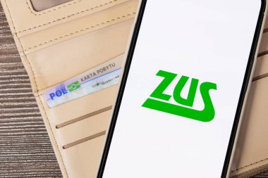 Poznan, Polonya - 20 Temmuz 2025: Ekranında ZUS logosunu gösteren bir akıllı telefon, Polonya sosyal sigorta sistemi bilgilerini yansıtıyor, bir cüzdanın yanına yerleştirilmiş bir Karta Pobytu