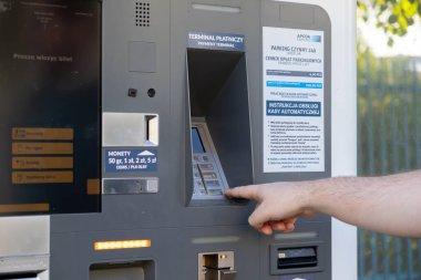 Poznan, Polonya - 10 Ağustos 2025: Otomatik park ödeme makinesiyle etkileşime giren bir kişinin elinin yakınlaştırılması, şehir araç park hizmetlerinin ücretlerini yönetmesi