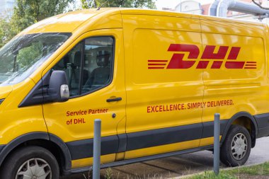 Poznan, Polonya - 10 Ağustos 2025: Açık sarı renkli bir DHL dağıtım minibüsü, verimli uluslararası kurye hizmetleri ve hızlı paket teslimatını ön plana çıkarıyor