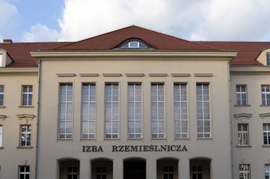 Poznan, Polonya - 10 Ağustos 2025: IZBA RZEMIESLNICZA, tarihi bir kurum binası, klasik cephe mimarisi, simetrik uzun pencereler ve karakteristik kırmızı kiremitli bir çatı sergiliyor
