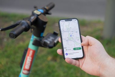 Poznan, Polonya - 10 Ağustos 2025: Bir kişinin elinde mevcut elektrikli scooterların bulunması için bir harita uygulaması gösteren bir akıllı telefon bulunuyor, modern kentsel ortak hareketliliği vurguluyor