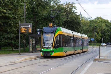 Poznan, Polonya - 10 Ağustos 2025: Yeşil ve sarı tramvay, sürdürülebilir kentsel hareketlilik için verimli modern toplu taşımacılığı vurguluyor