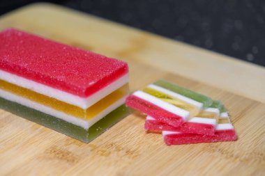 Canlı, çok katmanlı şekerleme bloğunun ve tatlı dilimlerin yakın görüntüsü, kutlama kutlamaları için leziz dokuları ve parlak renkleri gözler önüne seriyor.