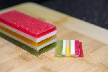 Kırmızı, beyaz, sarı ve yeşil kısımlı, şekerli yüzeyi olan, kültürel bir tatlı olarak ideal, canlı katmanlı jöleli kekin yakın çekimi.