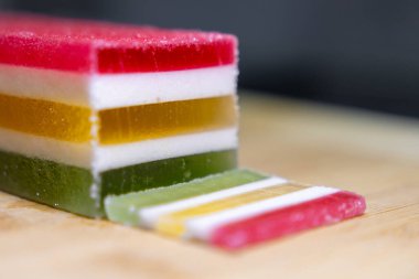 Tahta bir yüzey üzerinde canlı kırmızı, beyaz, sarı ve yeşil katmanlar gösteren çok katmanlı çok katmanlı bir şekerleme harika bir tatlı deneyim sunuyor.
