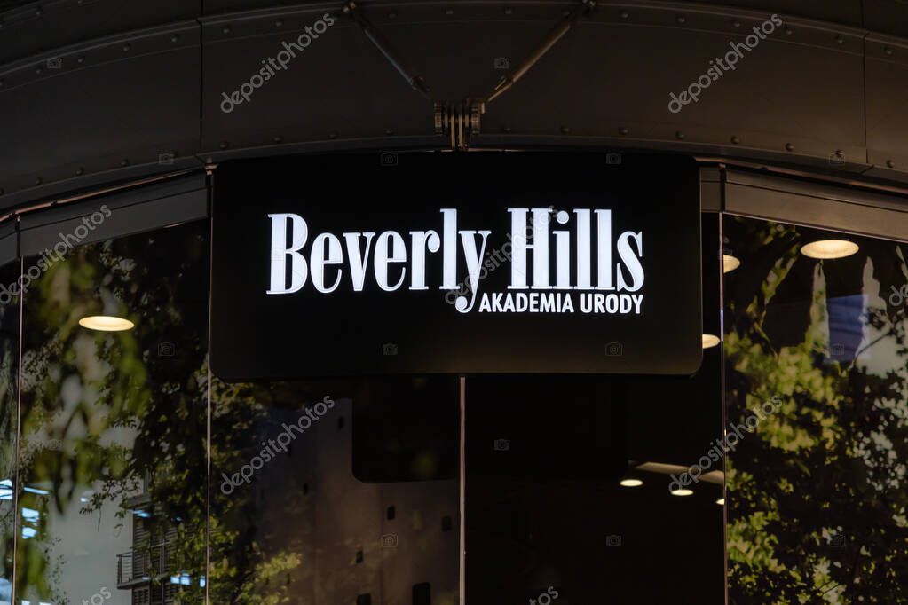 Poznan, Poland - September 5, 2025: Beverly Hills AKADEMIA URODY brand, brightly illuminated, displayed on modern building facade at night, reflecting urban surroundings