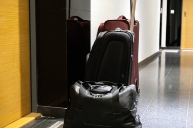 Modern seyahat valizleri, bir spor çantası ve iki bavul, bir otel koridorunda düzgünce düzenlenmiş, tatil, iş seyahati ya da gidiş için hazırlık anlamına gelir.
