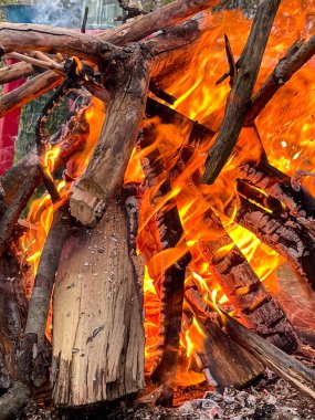 Şiddetli yanan büyük bir odun ateşinin yakın çekimi, dinamik turuncu ve sarı alevler sergiliyor, vahşi hayatta kalma, enerji ve sıcaklığı göstermek için ideal.
