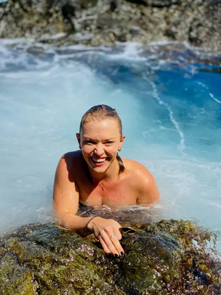 Kayaların arasında doğal bir havuzda mutlu bir kadın.
