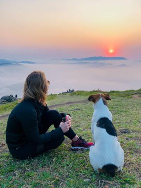 En iyi arkadaşı köpeğiyle güneşin doğuşunu izleyen bir kadın.