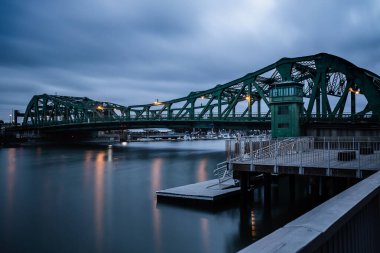 Alameda, California 'daki Park Street Köprüsü' nün uzun pozlu görüntüsü. Park Caddesi Köprüsü 'nün bu manzarası, iki dinamik Körfez Bölgesi toplumunu birbirine bağlayan hareketli bir su yolu ile köprü yapısını yakalar..