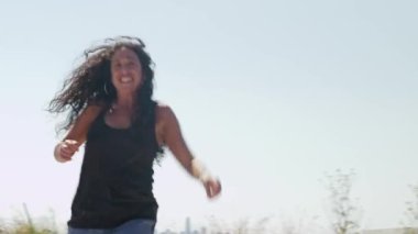 Alameda Rıhtım Parkı 'nda Latin bir hip hop dansçısı öğleden sonra güneşinin altında ritmini ve tarzını sergiliyor. Canlı dans, parkın sakin suları ve arka plandaki şehir manzarasıyla çelişiyor..