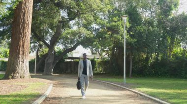 Huzurlu bir park bankına giderken, genç bir adam telefonuyla konuşuyor, açık havada çalışmaya hazırlanırken, üretken uzak çalışma gününe sakin bir başlangıç yapıyor..