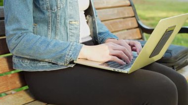 Laptop açık, duruş güçlü, genç, çok ırklı siyah bir kadın mahallenin parkında yaratıcı işler için yer açıyor..