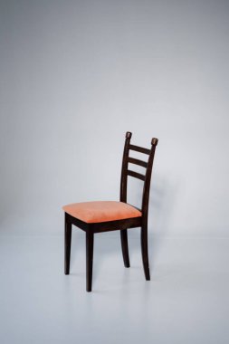 Beyaz odada tek tip ahşap sandalye tek başına duruyor.