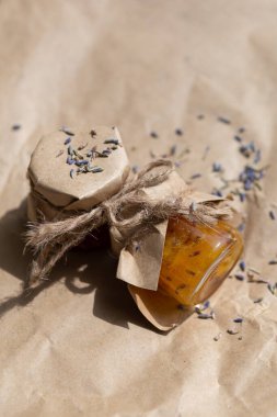 El yapımı portakal reçeli küçük bir kavanozda kağıdın üstünde. Lavanta en üstte görünüyor