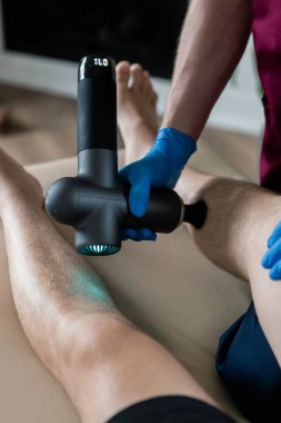 Doktor, perküsyon masaj tabancasıyla erkek bir hastanın dizine masaj yapıyor. - Evet. Yüksek kalite fotoğraf