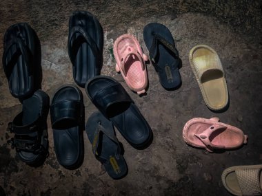 Düzensiz bir terasın önünde terlik koleksiyonu.