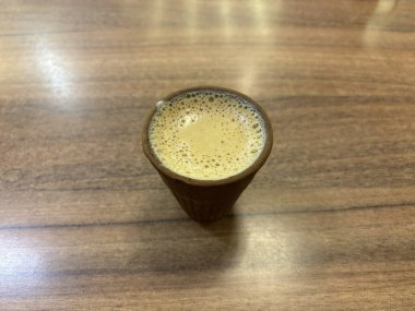 Geleneksel Hint masala çayı ahşap bir masaya konmuş topraktan yapılmış kilden bir bardakta servis edilir. Köpüklü çay, zengin aromasıyla Hindistan 'ın çay içme mirasının kültürel özünü vurgular..