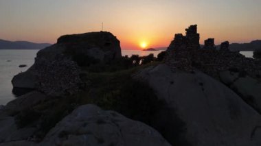 Bir adadaki eski harabelerin üzerinde gün batımı