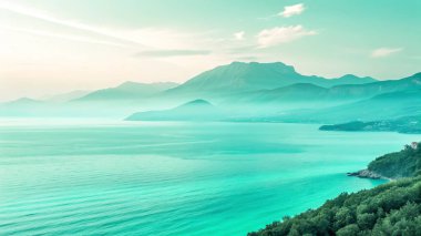 Uçsuz bucaksız, sakin bir turkuaz göl, yumuşak, puslu bir gökyüzünün altında sisli mavi renkli dağlara doğru uzanır. Yeşil, ağaçlarla kaplı bir kıyı şeridi uzaklığa doğru kıvrılır..