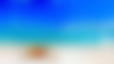 Beyaz kumlu bir plajda oturan bir insan, açık bir gökyüzünün altındaki turkuaz ve mavi okyanusa bakıyor..