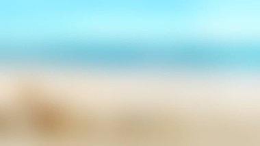 Sakin, bulanık bir kumsal görüntüsü berrak gökyüzünün altında yumuşak mavi okyanusla buluşuyor..