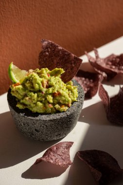 Beyaz arka planda mavi mısır ve tortilla cipsi ile guacamole porsiyonu