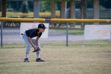 Sault Ste Marie, Ontario, Kanada - 5 Ağustos 2024: Genç beyzbol oyuncusu hazır ve odaklanmış. Sergide gençlik sporları, takım çalışması, sportmenlik ve açık hava eğlencelerinin heyecanı ve etkinliği gözler önüne seriliyor..