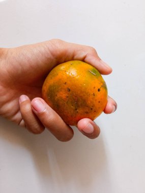 Beyaz tenli, turuncuyu tutan Asyalı kadın eli..