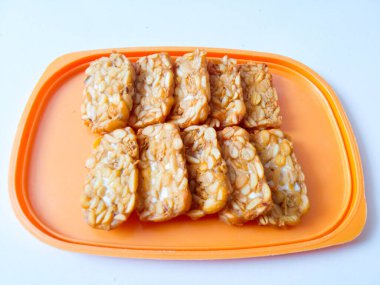 Kızarmış tempeh beyaz bir tabağa dizilmiştir.