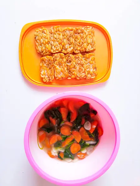 stock image Fried tempeh and a bowl of spinach and carrots are ready to eat