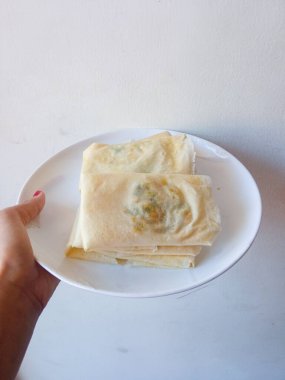 Martabak Telur Kulit Lumpia. Yumurta, et ve yeşil soğan dolgulu çıtır aperatifler. Yeşil biberle yenen favori sokak yemeği. Beyaz tabakta kızarmadan önce.