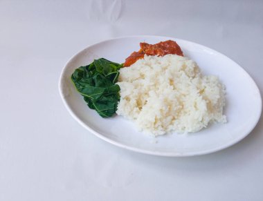 pirinç ve Padang rendang tavuklu meze ve manyok yapraklı sebzeler beyaz tabakta yalıtılmış.