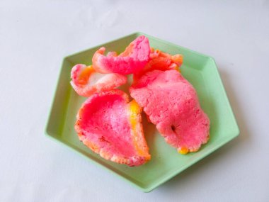 Yeşil bir altıgen tabaktaki çıtır pembe krakerler ve beyaz üzerinde izole edilmiş..