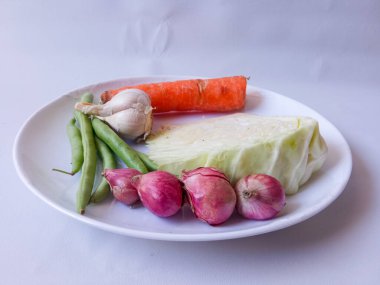 lahana, havuç, yeşil fasulye, tabakta kırmızı soğan sarımsağı ve beyazı izole et. Sağlıklı gıda konsepti. diyet menüsü kavramı