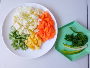 Patates dilimleri, lahana, havuç, yeşil fasulye, tabakta kırmızı soğan sarımsağı ve beyazı izole et. Sağlıklı gıda konsepti. diyet menüsü kavramı