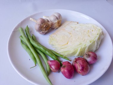 lahana, havuç, yeşil fasulye, tabakta kırmızı soğan sarımsağı ve beyazı izole et. Sağlıklı gıda konsepti. diyet menüsü kavramı