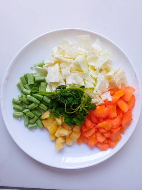 Patates dilimleri, lahana, havuç, yeşil fasulye, tabakta kırmızı soğan sarımsağı ve beyazı izole et. Sağlıklı gıda konsepti. diyet menüsü kavramı