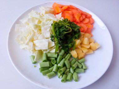 Patates dilimleri, lahana, havuç, yeşil fasulye, tabakta kırmızı soğan sarımsağı ve beyazı izole et. Sağlıklı gıda konsepti. diyet menüsü kavramı