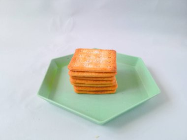 Şeker kaplı bisküviler, malkist olarak da bilinir, tatlı ve çıtır çıtır. Yeşil bir altıgen plaka ile beyaza izole edilmiş. abur cubur