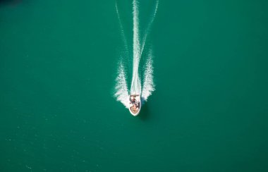 Montynard Avignonet Gölü 'nün (Lac de Montynard-Avignonet) eteklerindeki Passerelle du Drac Footbridge' den (Drac Footbridge) görülen bir sürat teknesi, Fransa 'nın Mayres-Savel, Isere, Alplerin eteklerinde güç kaybediyor.