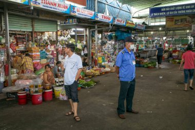 Üniformalı bir güvenlik görevlisi ve alışveriş yapan bir kişi Con Market, Danang, Vietnam 'da yan yana dururlar..
