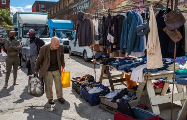 Yaşlı bir adam İngiltere 'nin doğusundaki Brick Lane Market' te ikinci el kıyafet dükkanının önünden geçiyor.