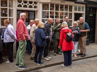 Bir grup yaşlı turist, İngiltere 'nin Kuzey Yorkshire kentinin merkezindeki ünlü antik cadde olan Shambles' da bir dükkanın önünde duruyor.