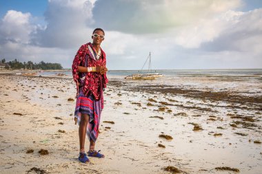 Genç bir Masai savaşçısı Jambiani sahilinde geleneksel shuka yapıyor, Zanzibar, Tanzanya