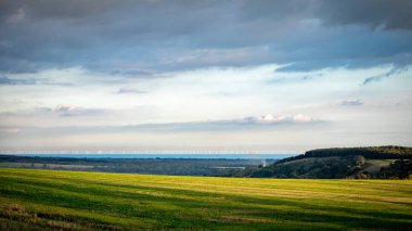 Güney Downs Ulusal Parkı, Batı Sussex, İngiltere 'de öğleden sonra tarlalar ve açık deniz rüzgar çiftliğine doğru bir manzara.