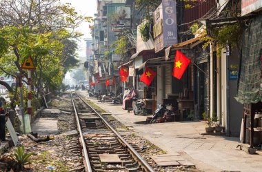 Vietnam 'ın başkenti Hanoi' de Le Duan Caddesi 'nden geçerken Hanoi ile Ho Chi Minh Şehri' ni birbirine bağlayan ana kuzey-güney demiryolu hattının yanındaki kirli sis bulutlarında Vietnam bayrakları dalgalanıyor..