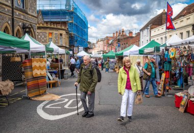 Yaşlı bir çift, Winchester, Hampshire, İngiltere 'de hafta sonu antikacılık ve zanaat pazarında yürüyor.